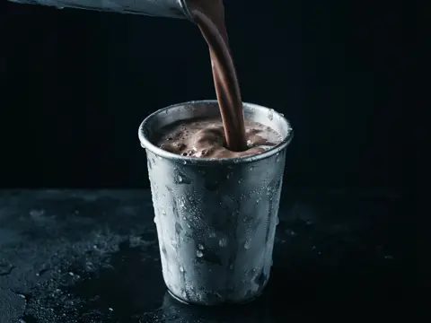 Concept imagery: a thick milkshake pouring into a frosted metal tin